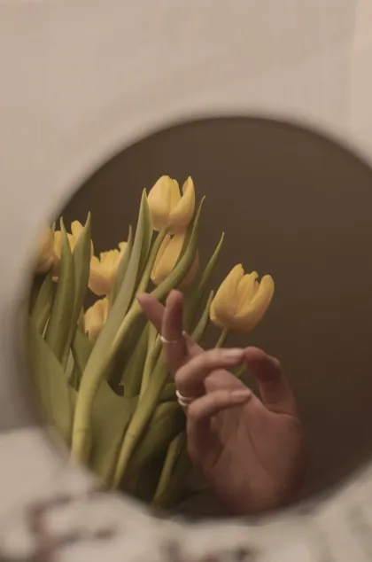 Ramo de tulipanes amarillos reflejado en un espejo redondo